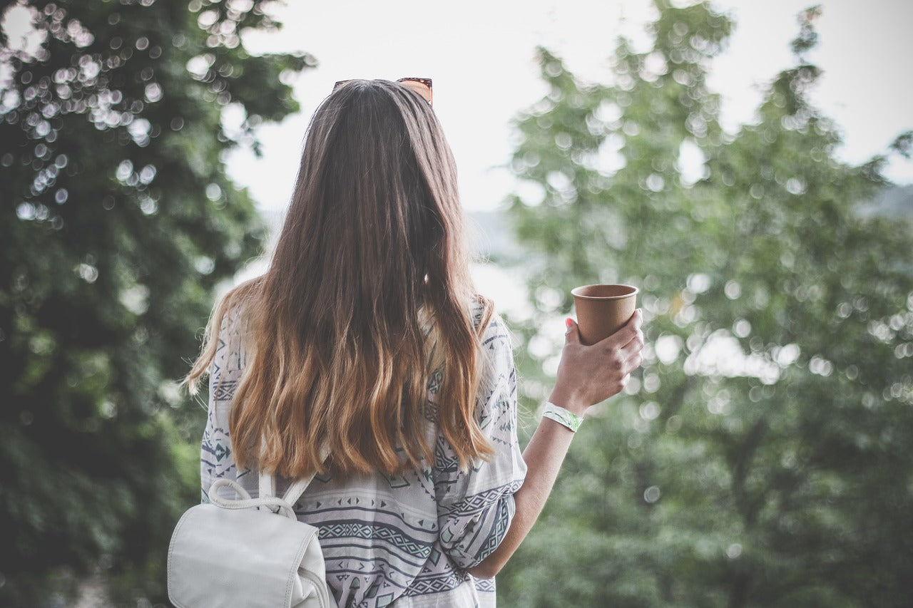 Girl with beautiful long gorgeous brown ombre hair holding a cup of coffee enjoying the weather outdoors outside